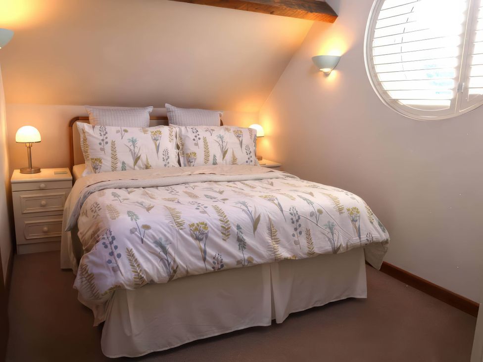 A bedroom with a bed and a bedside lamp at Acorn Cottage in Knutsford