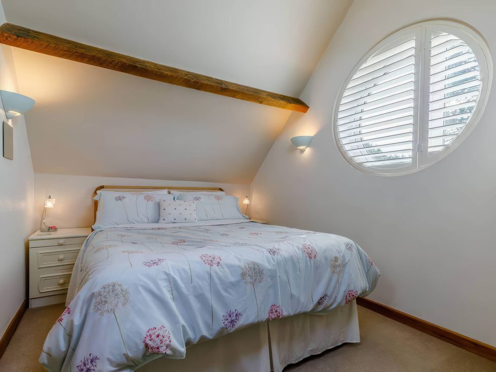 A bedroom with a bed and a nightstand at Acorn Cottage in Knutsford