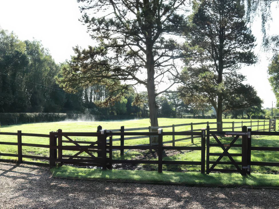 An outdoor scene with a wooden fence and gate at Acorn Cottage in Knutsford