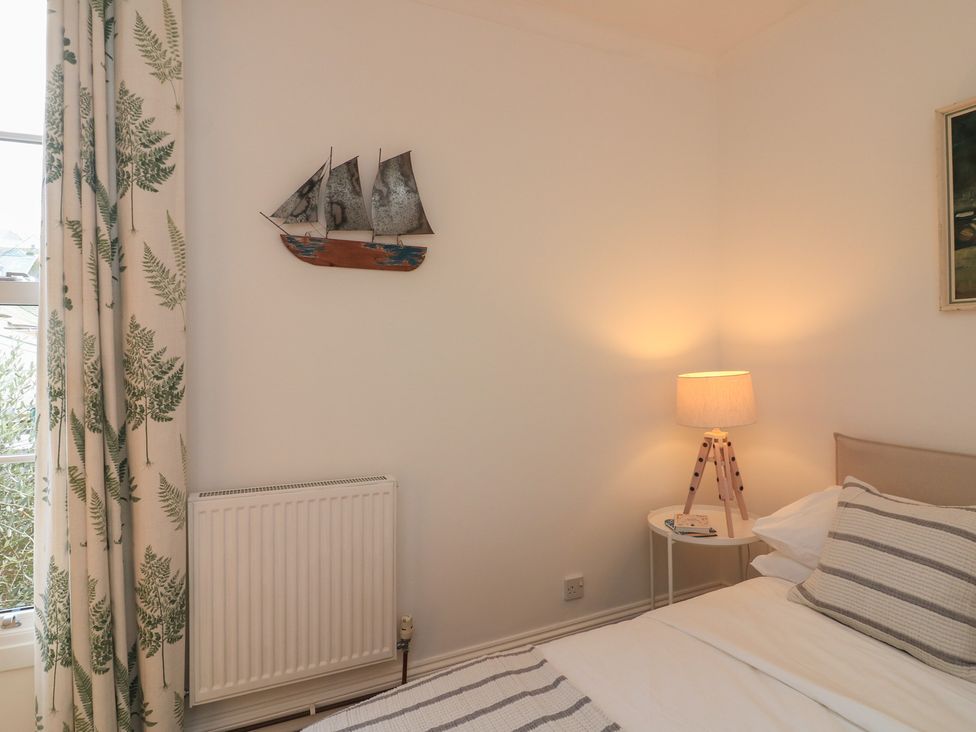 A bedroom with a bed, lamp, and wall decoration at Ivy Cottage in Dartmouth