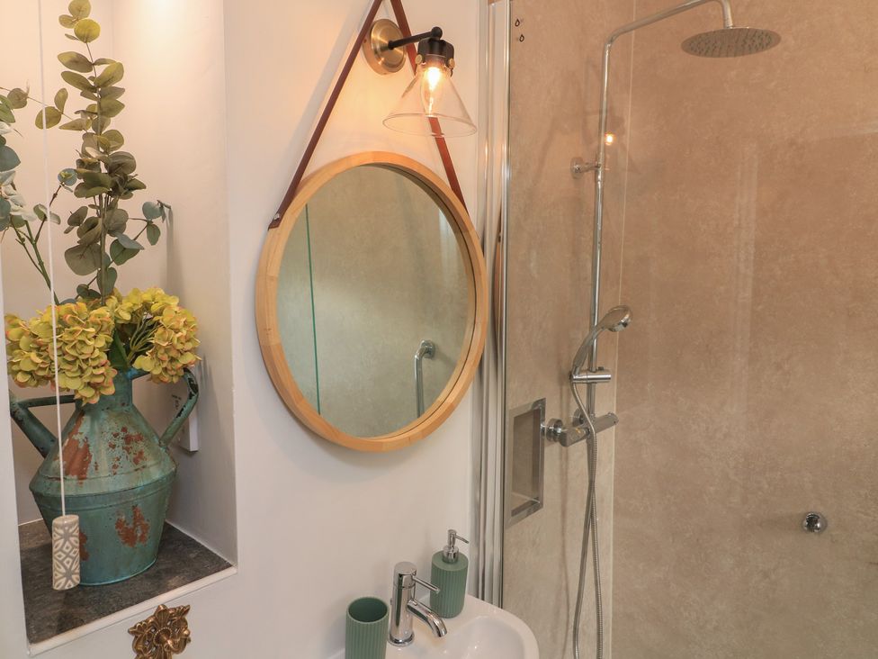 A shower area with a mirror and sink at Ivy Cottage in Dartmouth