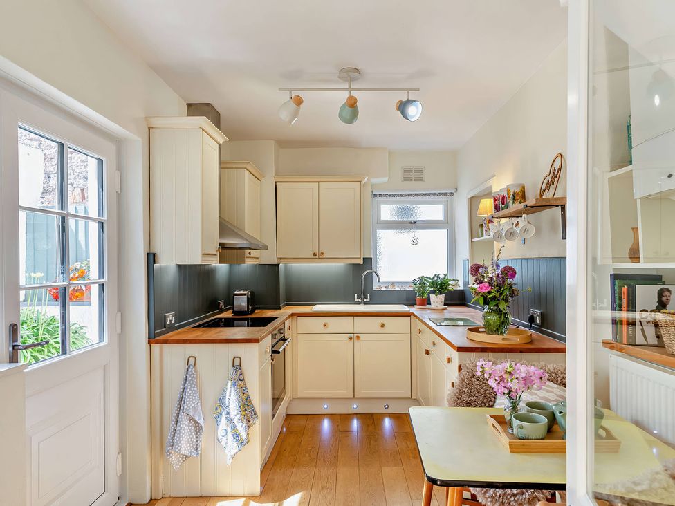 A kitchen with cabinets and a table at Ivy Cottage Dartmouth
