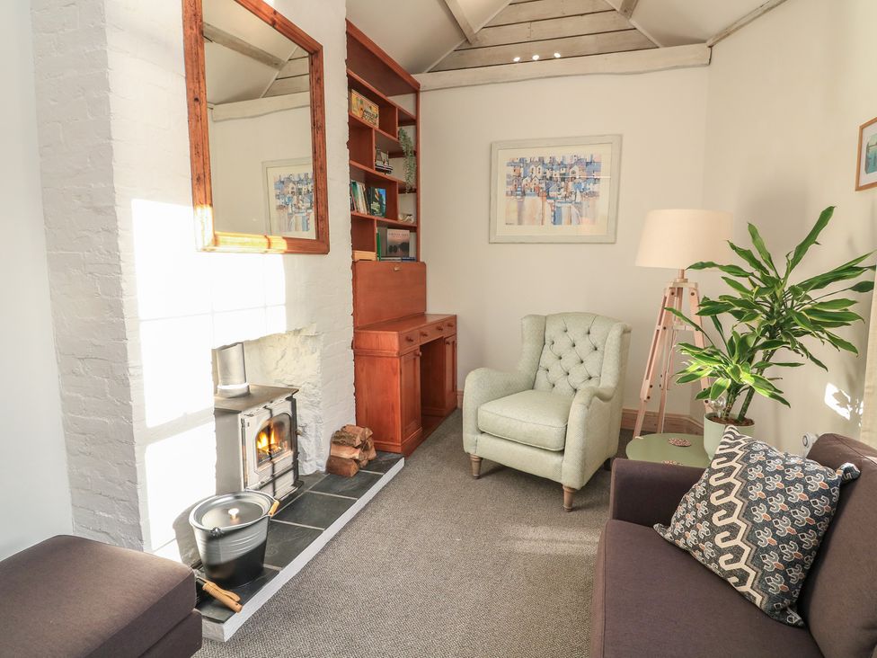 A living room with a fireplace and armchair at Ivy Cottage in Dartmouth