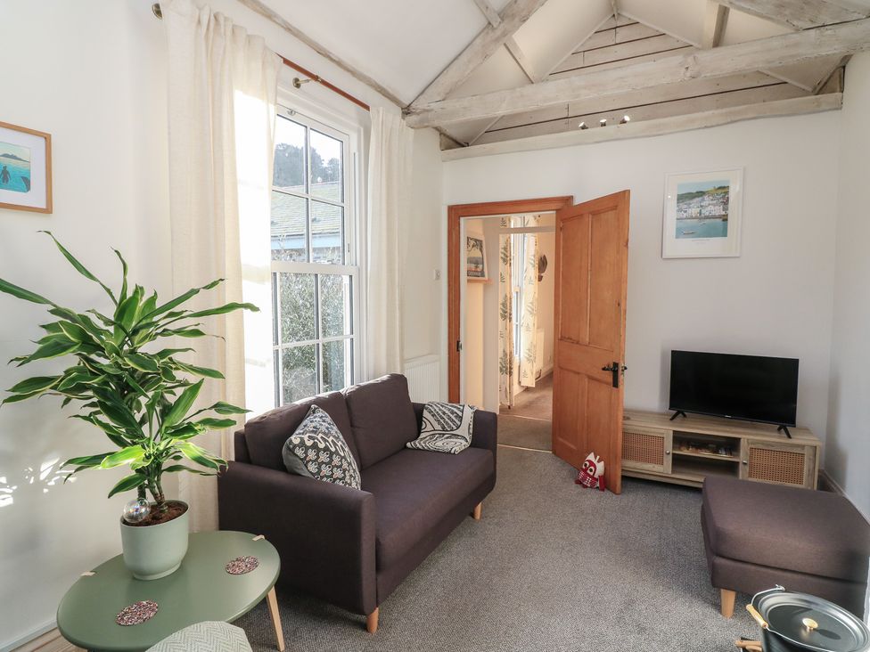 A living room with a sofa and a TV stand at Ivy Cottage Dartmouth