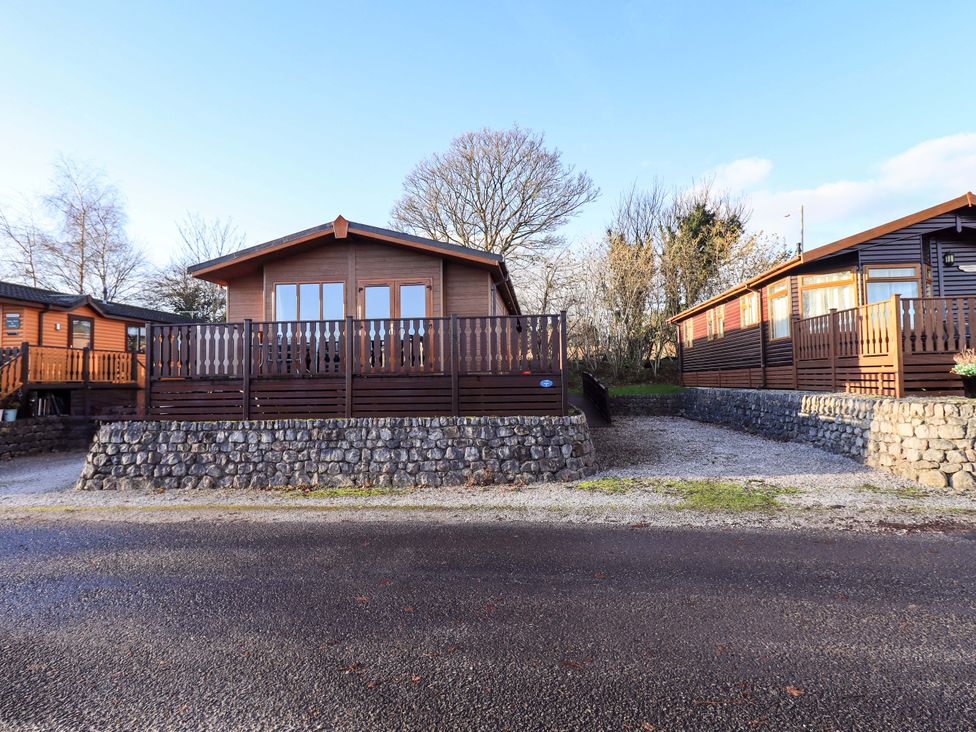 Log cabin with wooden deck and stone wall at Kingfisher Lodge