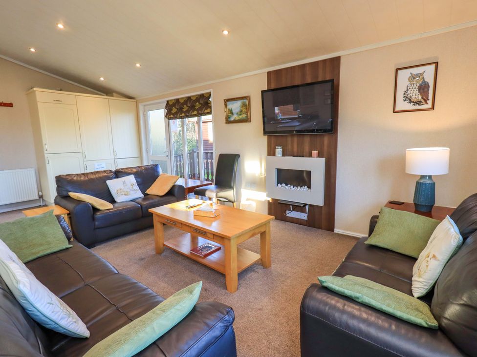 A living room with a television and coffee table at Kingfisher Lodge