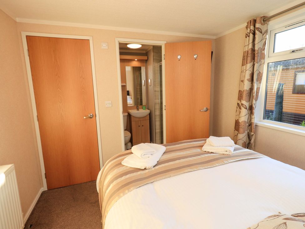 A bedroom with a bed and bathroom entrance at Kingfisher Lodge