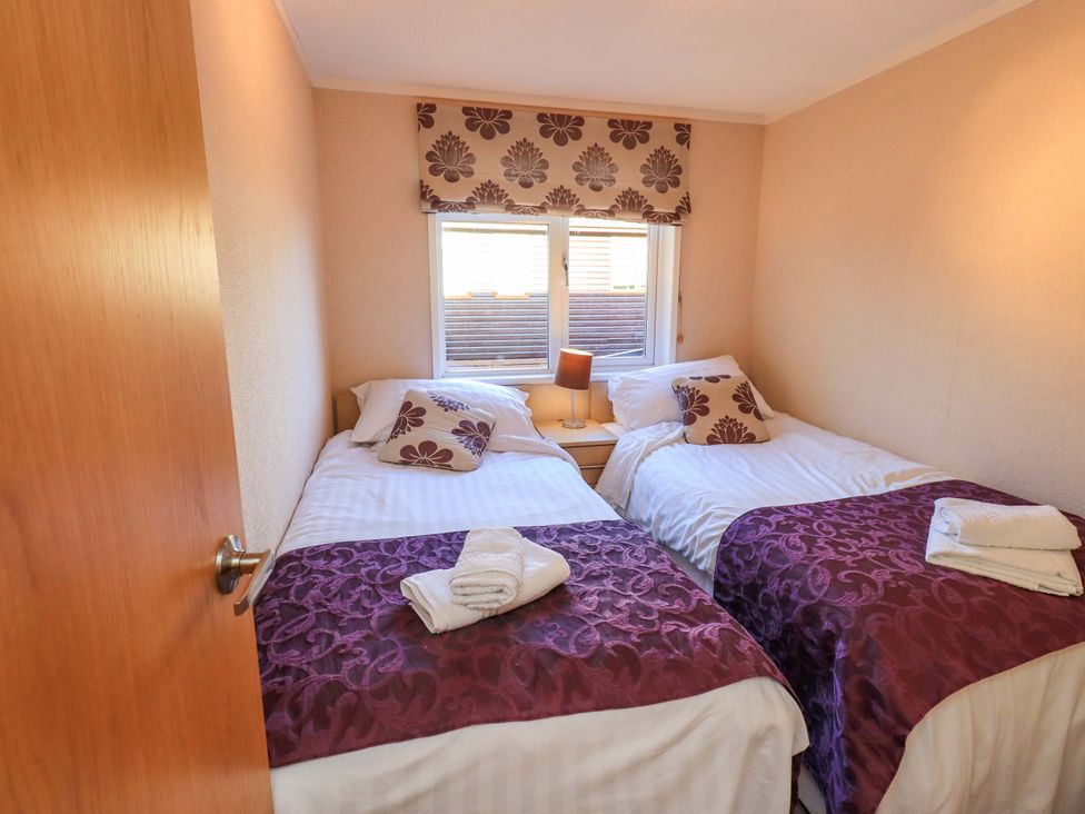A bedroom with two beds and a lamp at Kingfisher Lodge