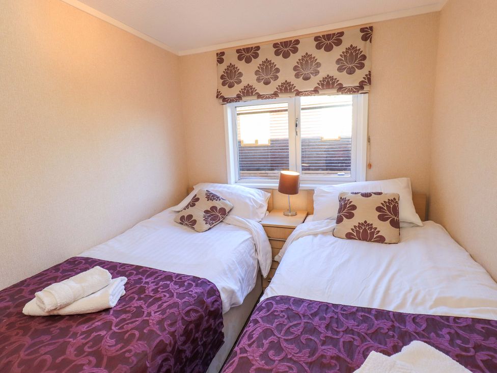A bedroom with two beds and a lamp at Kingfisher Lodge 