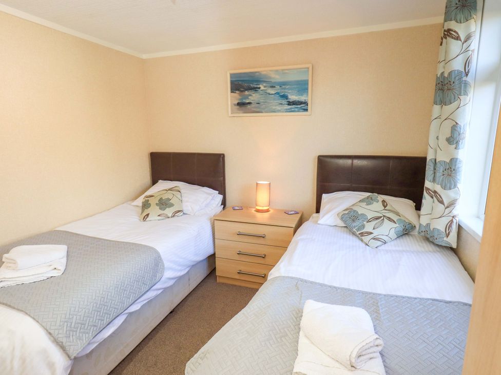 A bedroom with two single beds and a nightstand at Kingfisher Lodge