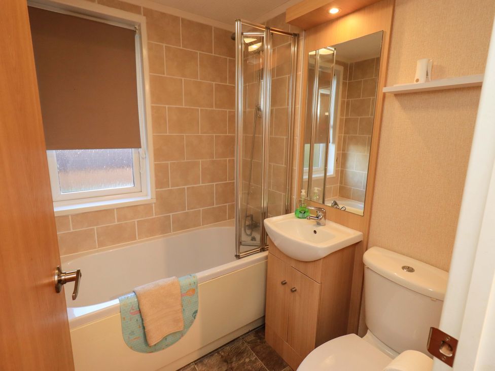 A bathroom with a bathtub, shower, sink and toilet at Kingfisher Lodge