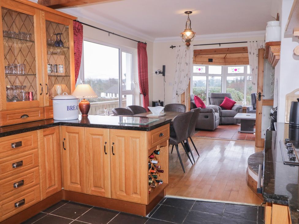 A kitchen with wooden cabinets and a living area at Bungalow Falcarragh, Falcarragh, County Donegal
