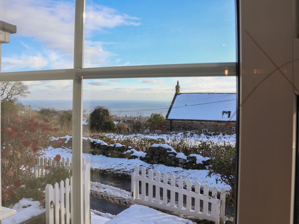 A view of the ocean and snow-covered ground from a window at Cheyne Cottage in Fylingthorpe