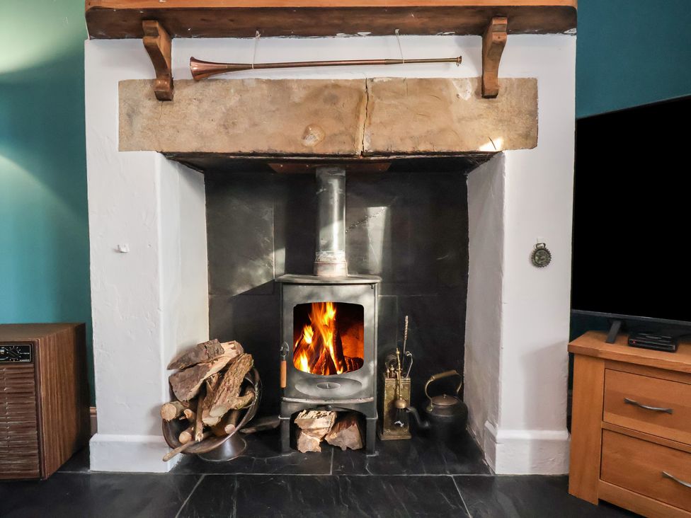 A fireplace and wood stove in a living room at Cheyne Cottage Fylingthorpe