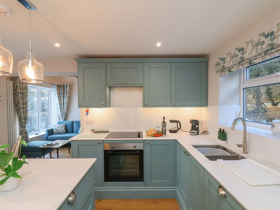 A kitchen with cabinets, oven, and sink at Cheyne Cottage Fylingthorpe