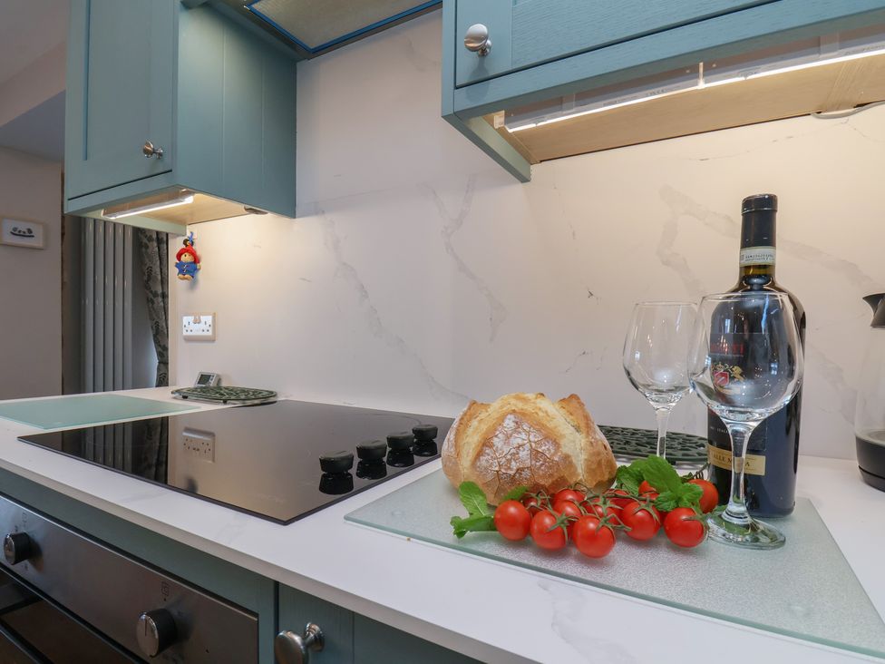 A kitchen with cooking stove, bread, tomatoes, and wine at Cheyne Cottage in Fylingthorpe