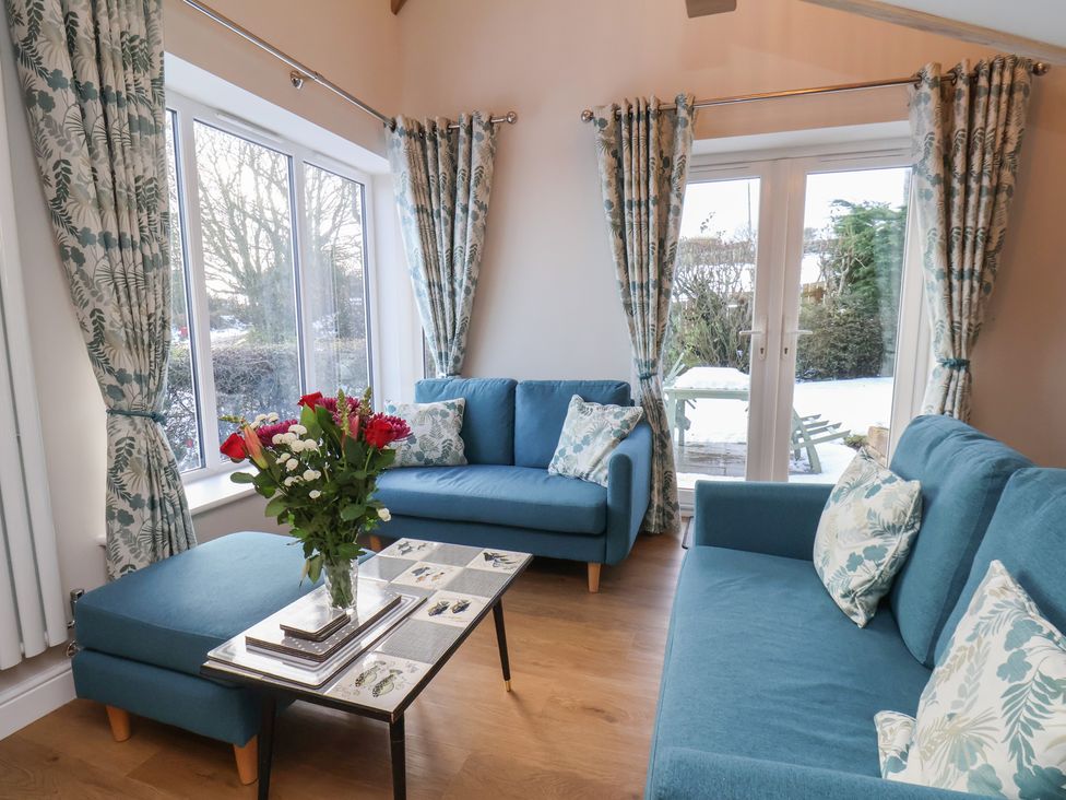 A living room with sofas and flowers at Cheyne Cottage in Fylingthorpe