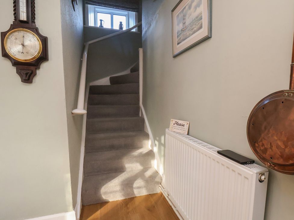 A hallway with a staircase and wall decor at Cheyne Cottage in Fylingthorpe