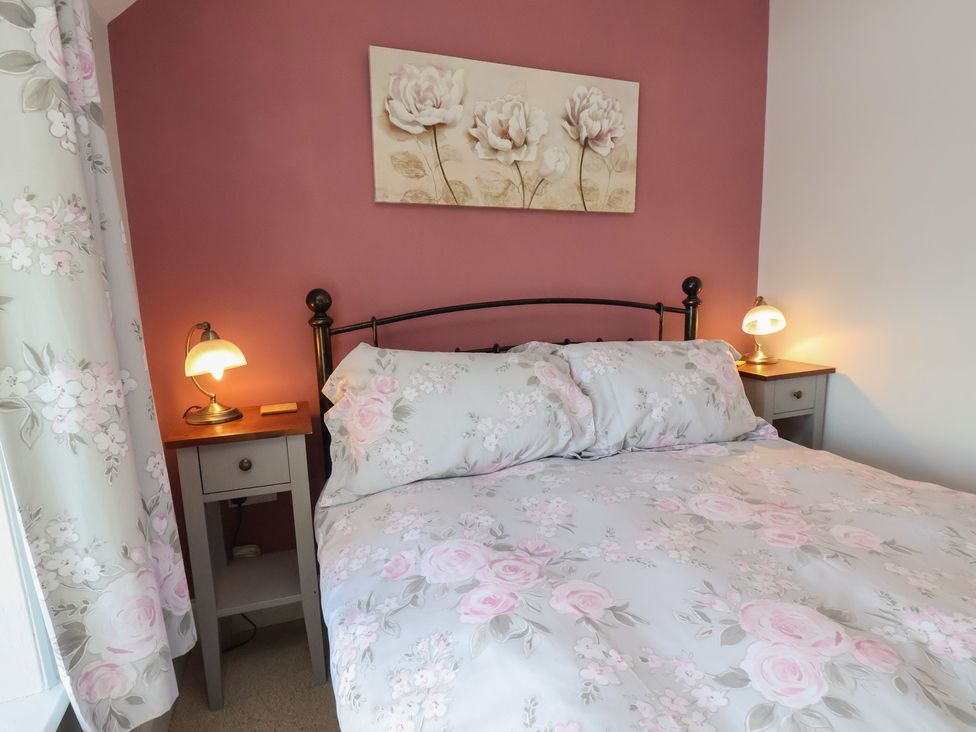 A bedroom with a bed and nightstand at Cheyne Cottage in Fylingthorpe