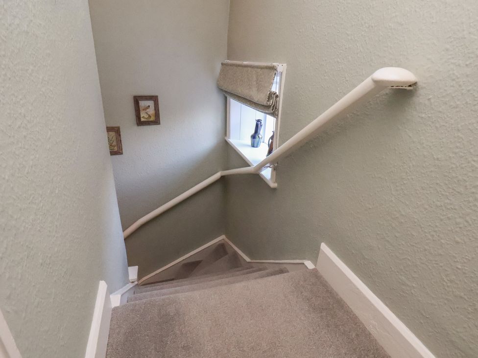 A staircase with a handrail and framed pictures at Cheyne Cottage in Fylingthorpe