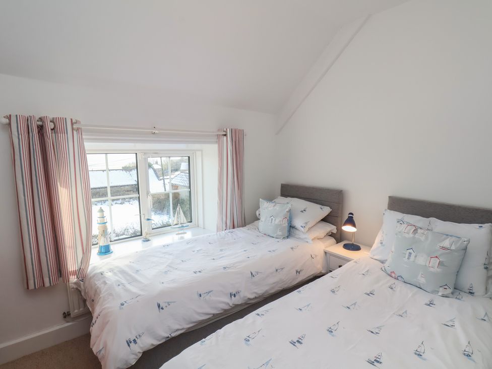 A bedroom with two beds and a window at Cheyne Cottage in Fylingthorpe