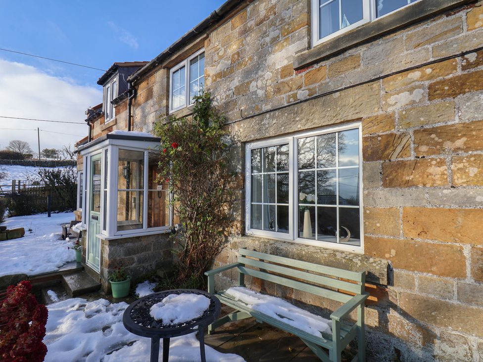 An exterior view of a house with a bench and windows at Cheyne Cottage in Fylingthorpe