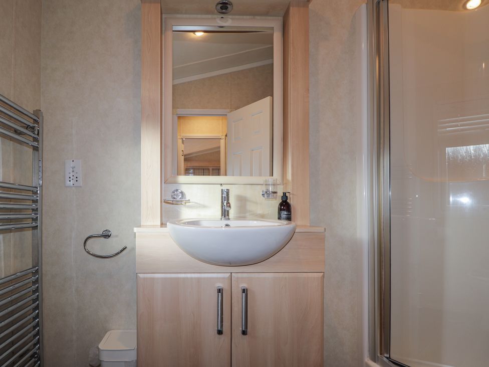 A bathroom with a sink, mirror, towel rail, and shower at Monach 1