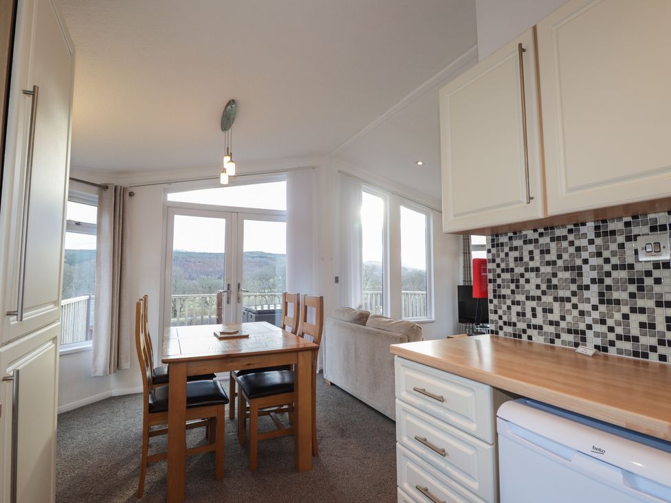 A dining room with a table and chairs and kitchen appliances at Colonsay