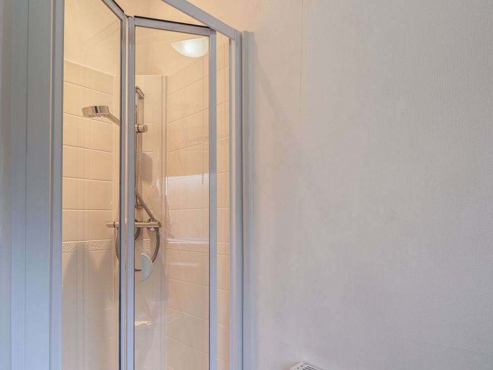 A shower enclosure with a showerhead and tiled walls at Colonsay