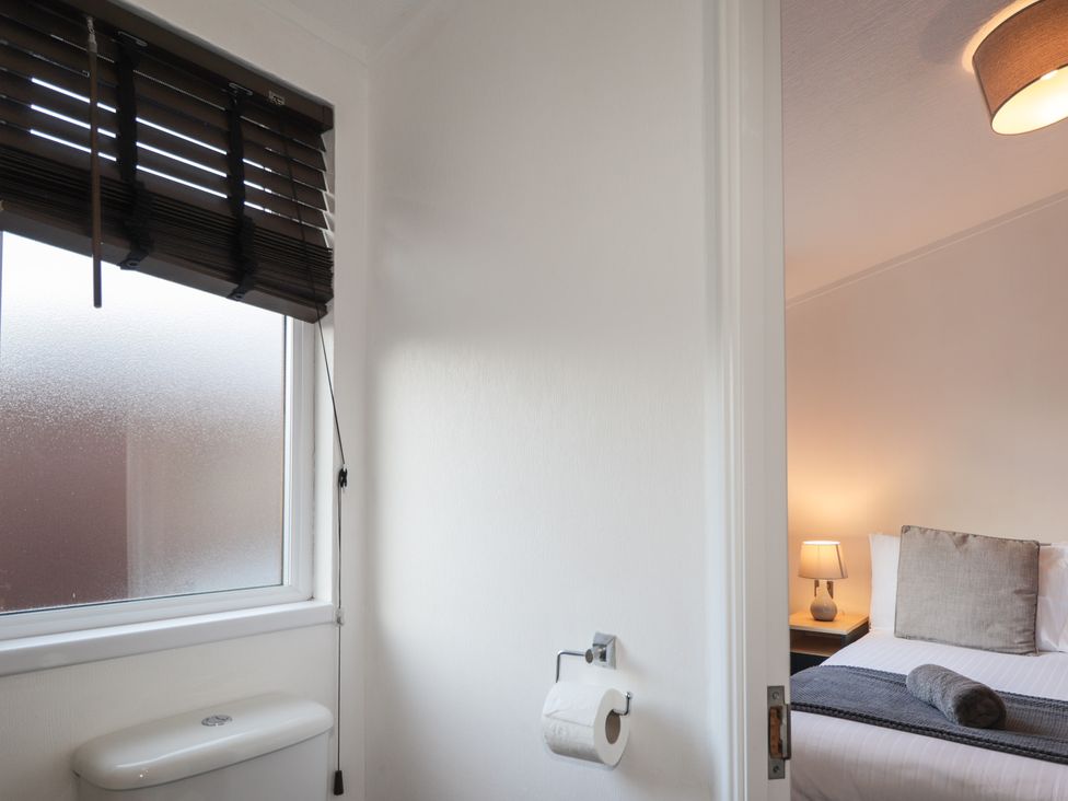 A bathroom with a toilet and window leading to a bedroom at Colonsay
