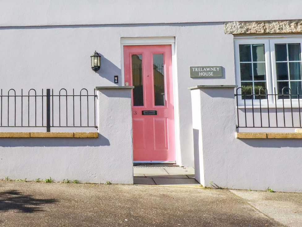A pink door with a light fixture and nameplate at Trelawney House in St. Austell