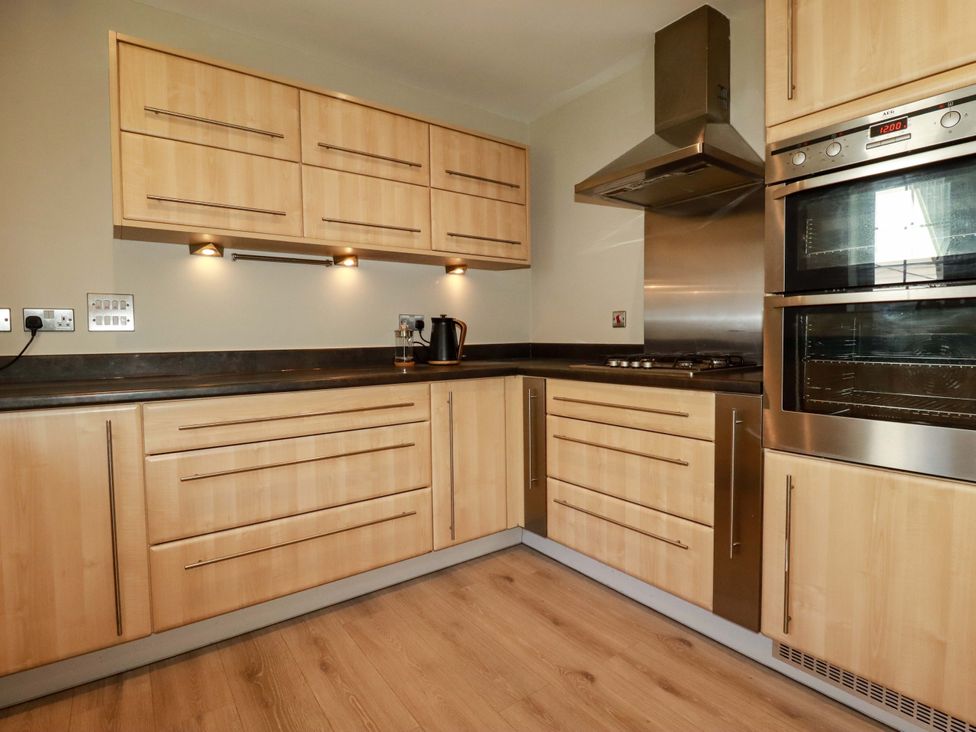 A kitchen with wooden cabinets and appliances at 3 Rope Walk in St. Austell