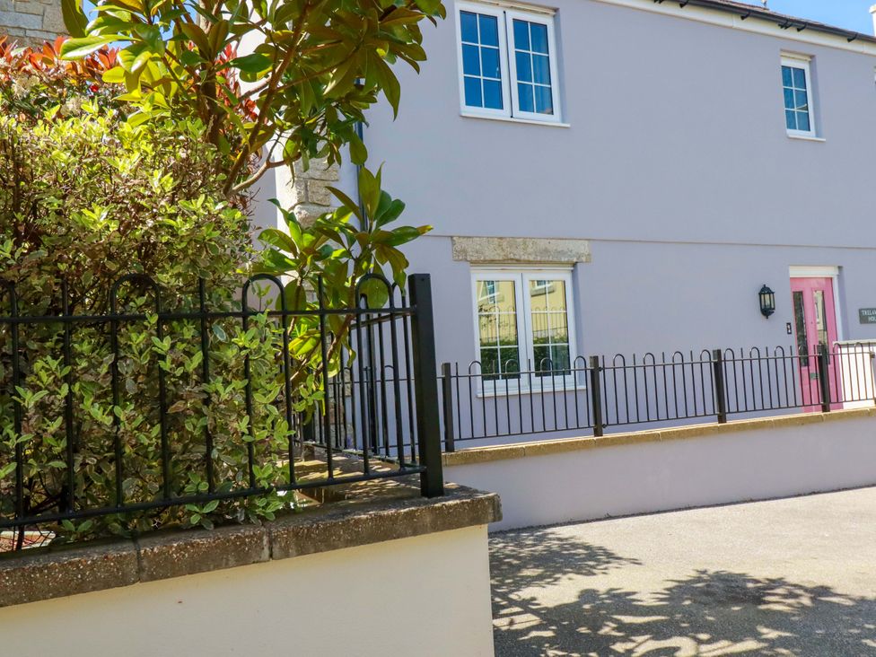 An outdoor view of a house with windows and a pink door at Trelawney House Duporth near Charlestown