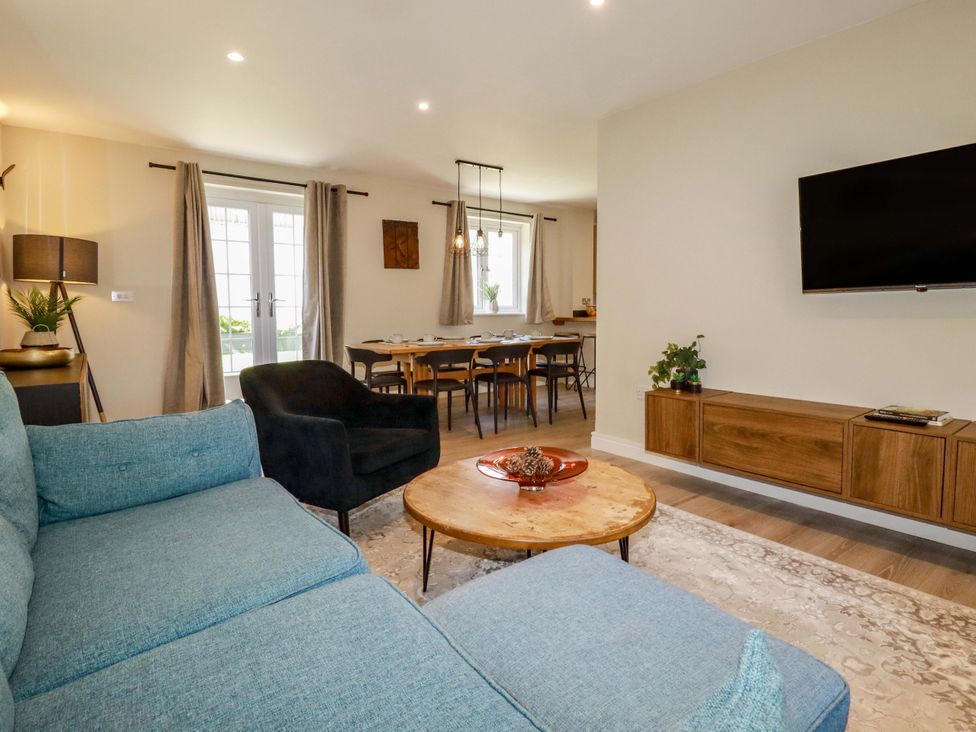 A living room with a sofa and dining area at Trelawney House in Duporth near Charlestown