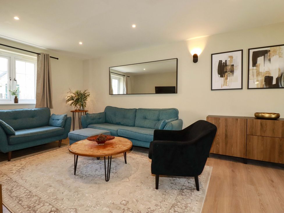 A living room with a sofa, armchair, and coffee table at Trelawney House in Duporth near Charlestown