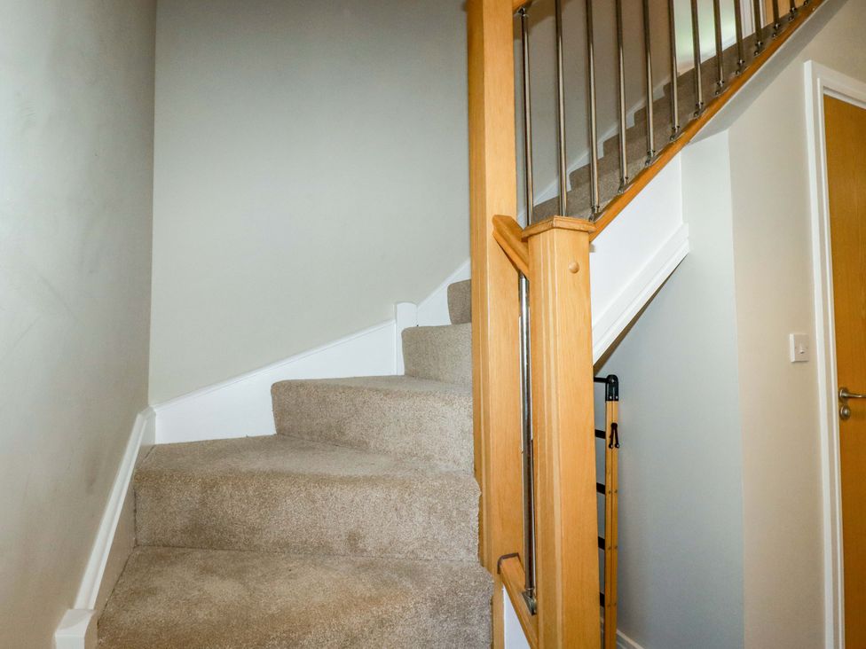 A staircase with carpet and wooden handrail at Trelawney House Duporth near Charlestown