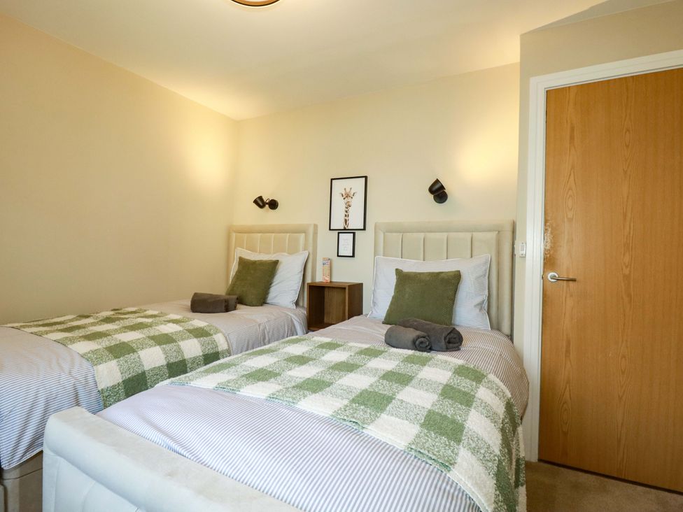 A bedroom with twin beds and a nightstand at Trelawney House in Duporth near Charlestown