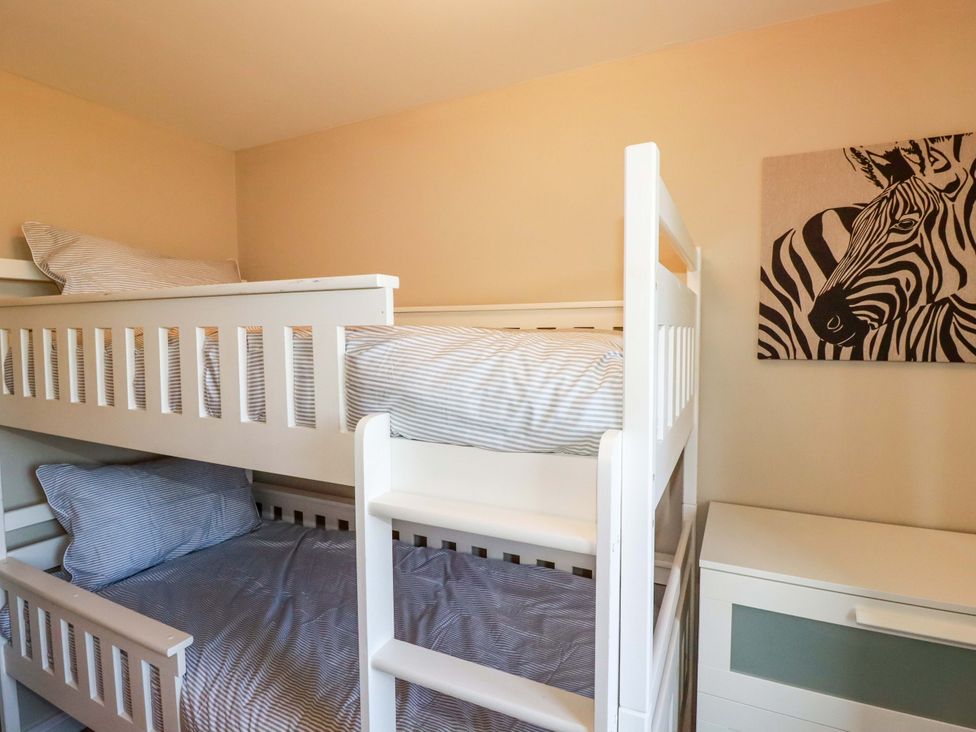 A bunk bed with striped bedding and wall art at Trelawney House in Duporth near Charlestown