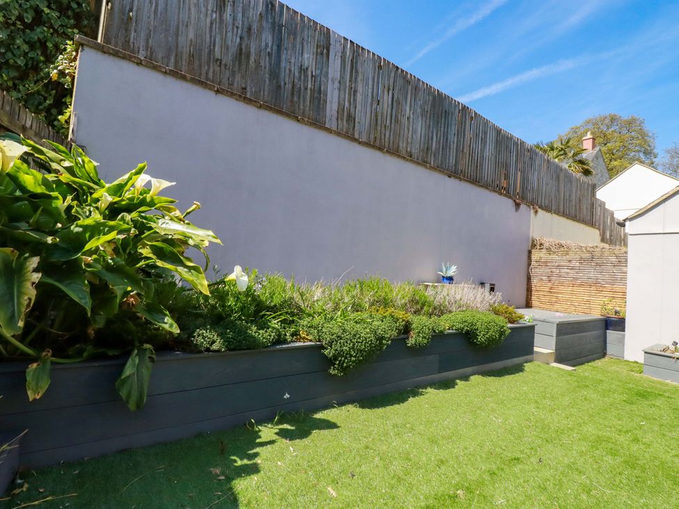 A garden with plant beds and a wooden fence at Trelawney House Duporth near Charlestown