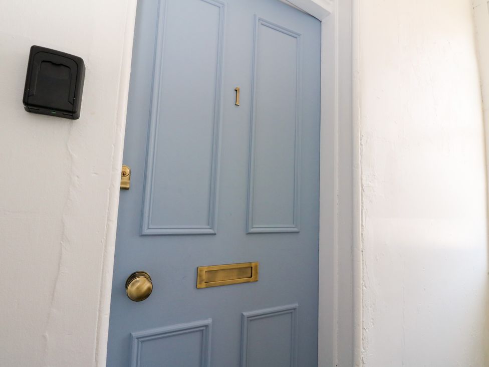 A blue door with a mail slot and door number at Flat 1
