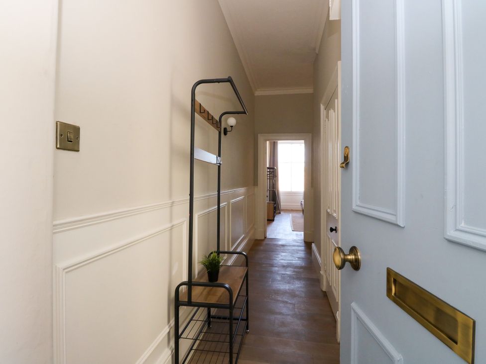 A hallway with a coat rack and plant at Flat 1 in 