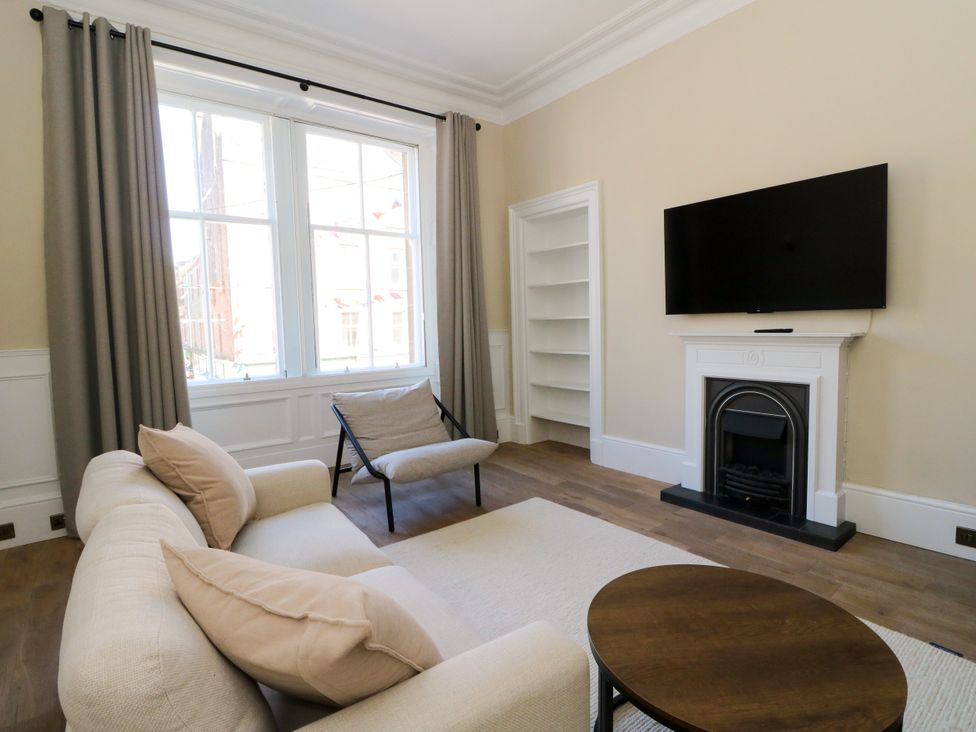 A living room with a sofa and television at Flat 1