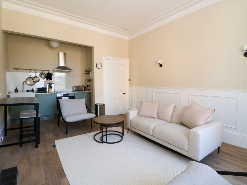 A living room with a kitchen area and furniture at Flat 1