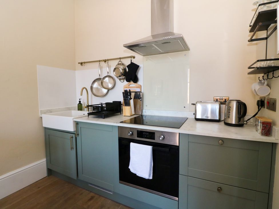 A kitchen with a sink, cooker, and various appliances at Flat 1