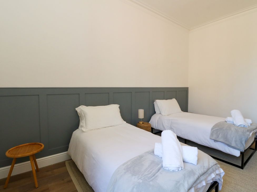 A bedroom with two beds and a side table at Flat 1
