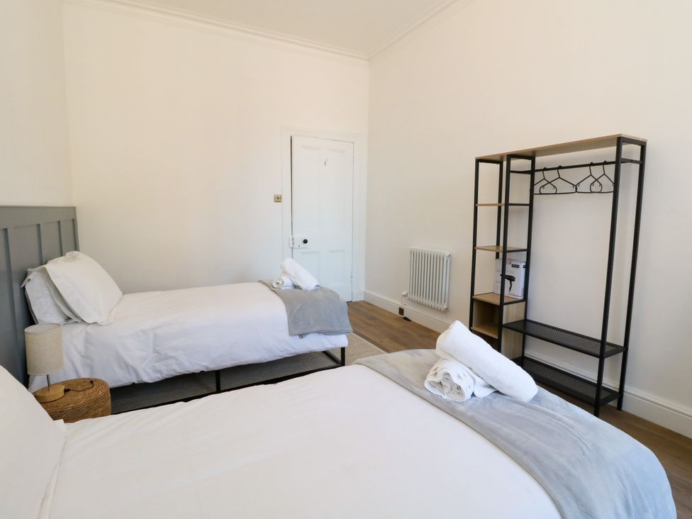 A bedroom with two beds and a dresser at Flat 1
