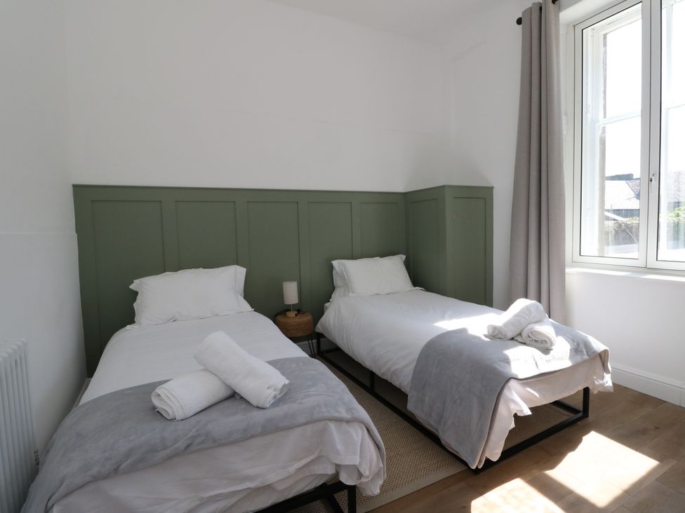A bedroom with two single beds and a window at Flat 1