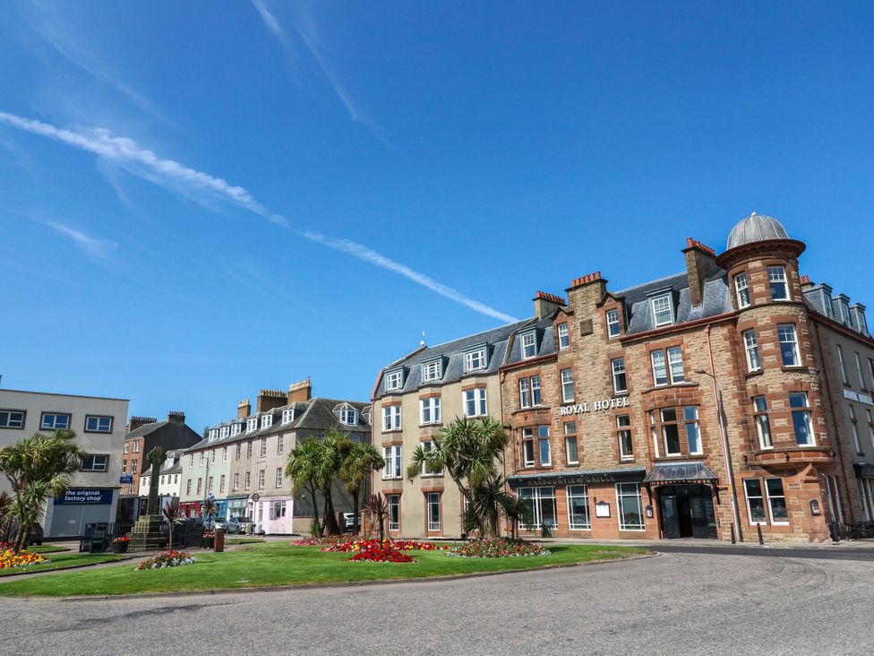 A street view featuring buildings and flower beds at Flat 1