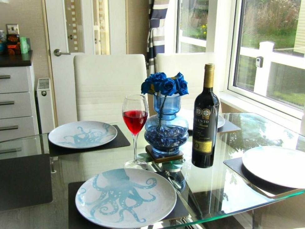 A dining table with plates, a glass of red drink, and a wine bottle at Seton Sands Caravan Park - Holiday Accommodation 13391, Cockenzie And Port Seton