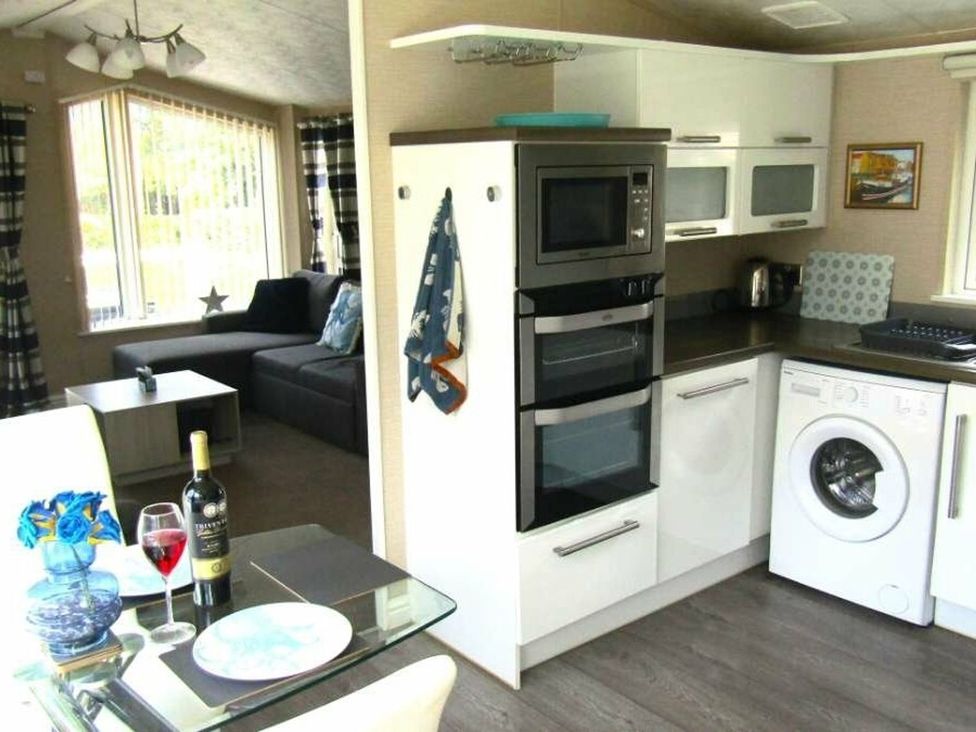 A kitchen area with a washing machine and sofa at Seton Sands Caravan Park - Holiday Accommodation 13391 Cockenzie And Port Seton
